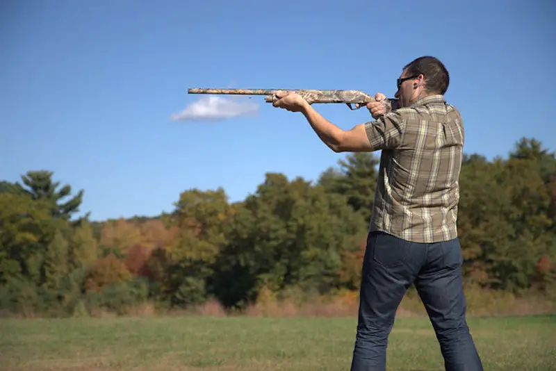 Man holding a gun is doing a skeet shooting